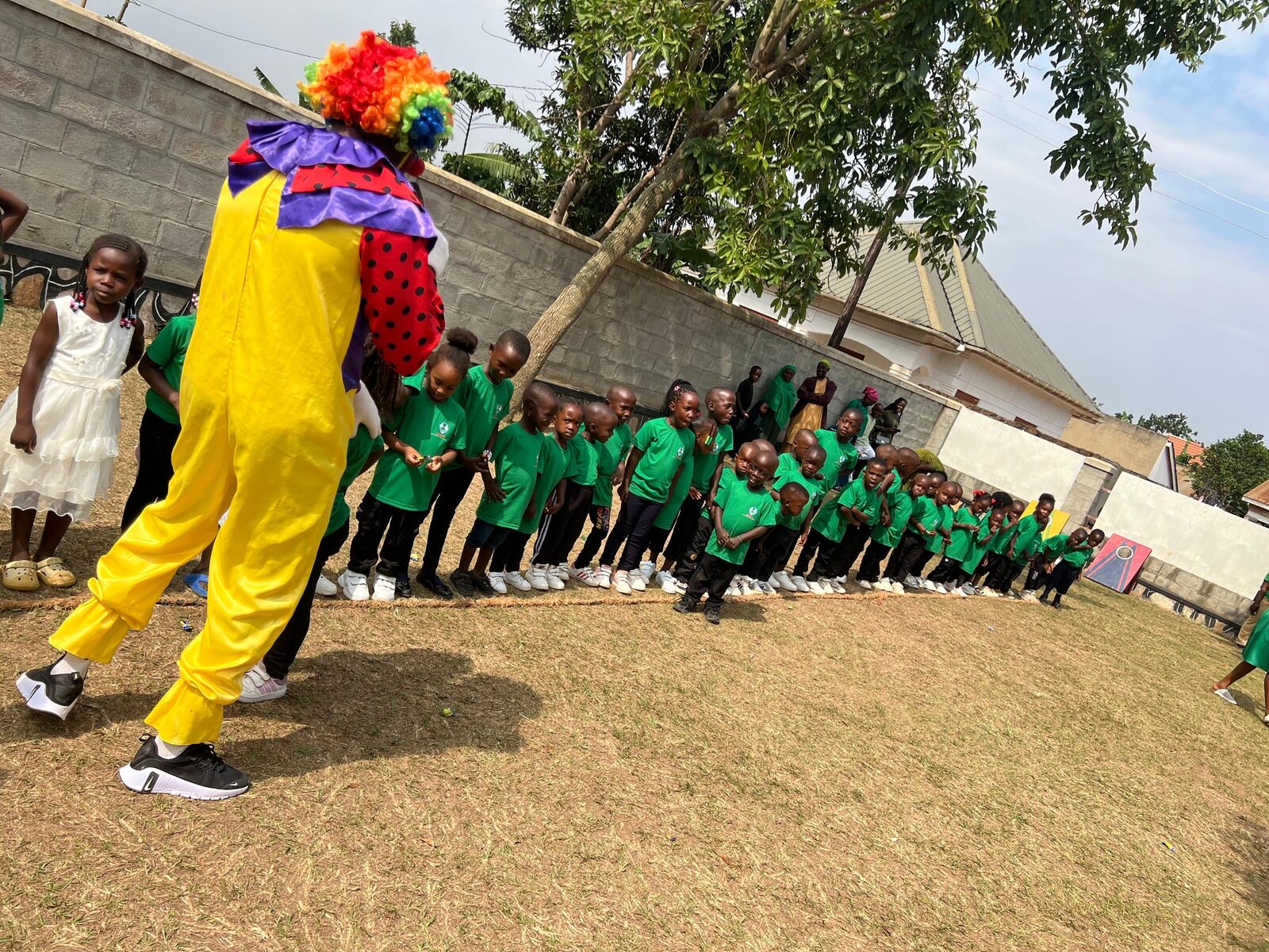 A costumed entertainer performing for a line of children in green Goshen shirts