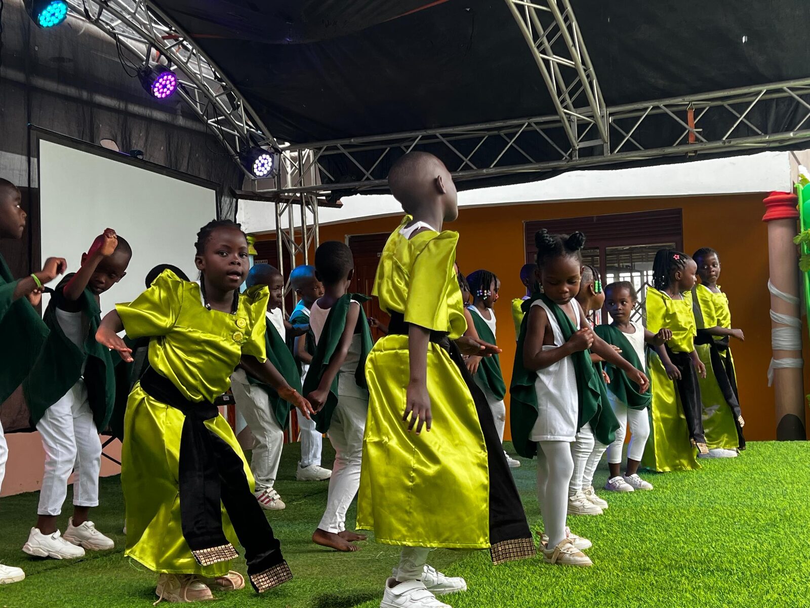 Children performing a coordinated dance on stage during Green Color Day