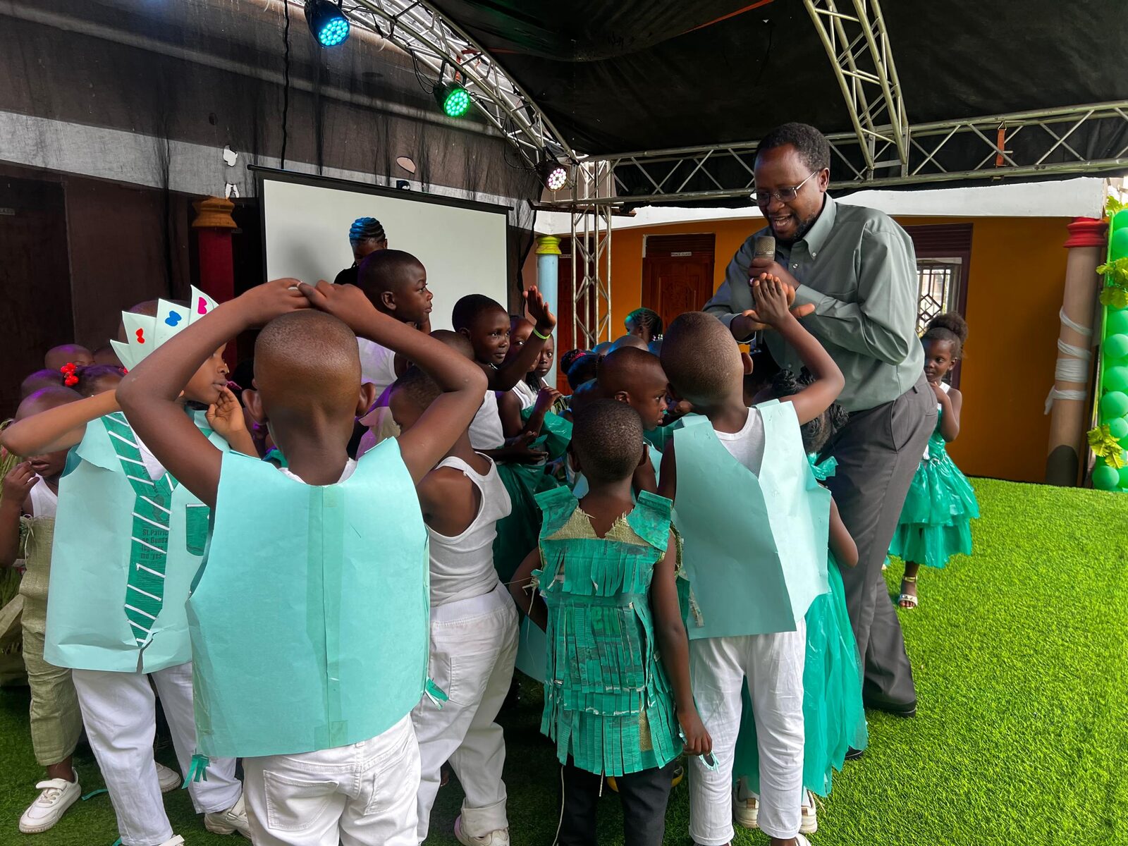 A joyful moment between children and a staff member holding a microphone